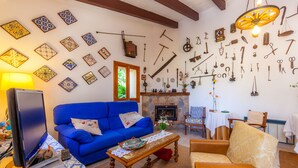 Una sala de estar con un sofá azul, una mesa de centro de madera, una chimenea y una pared decorada con diversas herramientas y azulejos.
