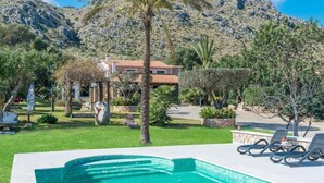 A swimming pool with a mountain backdrop, a house with a red roof, and a palm tree. - Villa with mountain view and pool - Es Puchet (Alcudia)