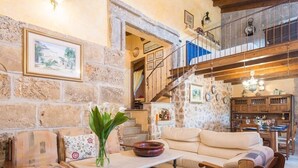 A cozy living area with a stone wall, a sofa, a coffee table, and a staircase leading to an upper level. - Villa with mountain view and pool - Es Puchet (Alcudia)