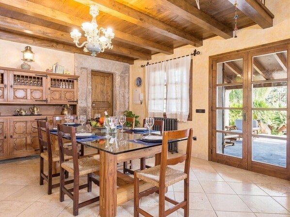 Comedor con una mesa de vidrio, sillas de madera, una araña y vistas amplias a través de grandes ventanales.
