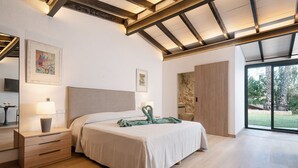 A modern bedroom with a bed, bedside tables, a wardrobe, and a large window. - Villa with mountain view and pool - Es Puchet (Alcudia)