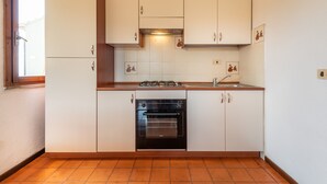 Een keuken met witte kastjes, een ingebouwde oven en een raam.