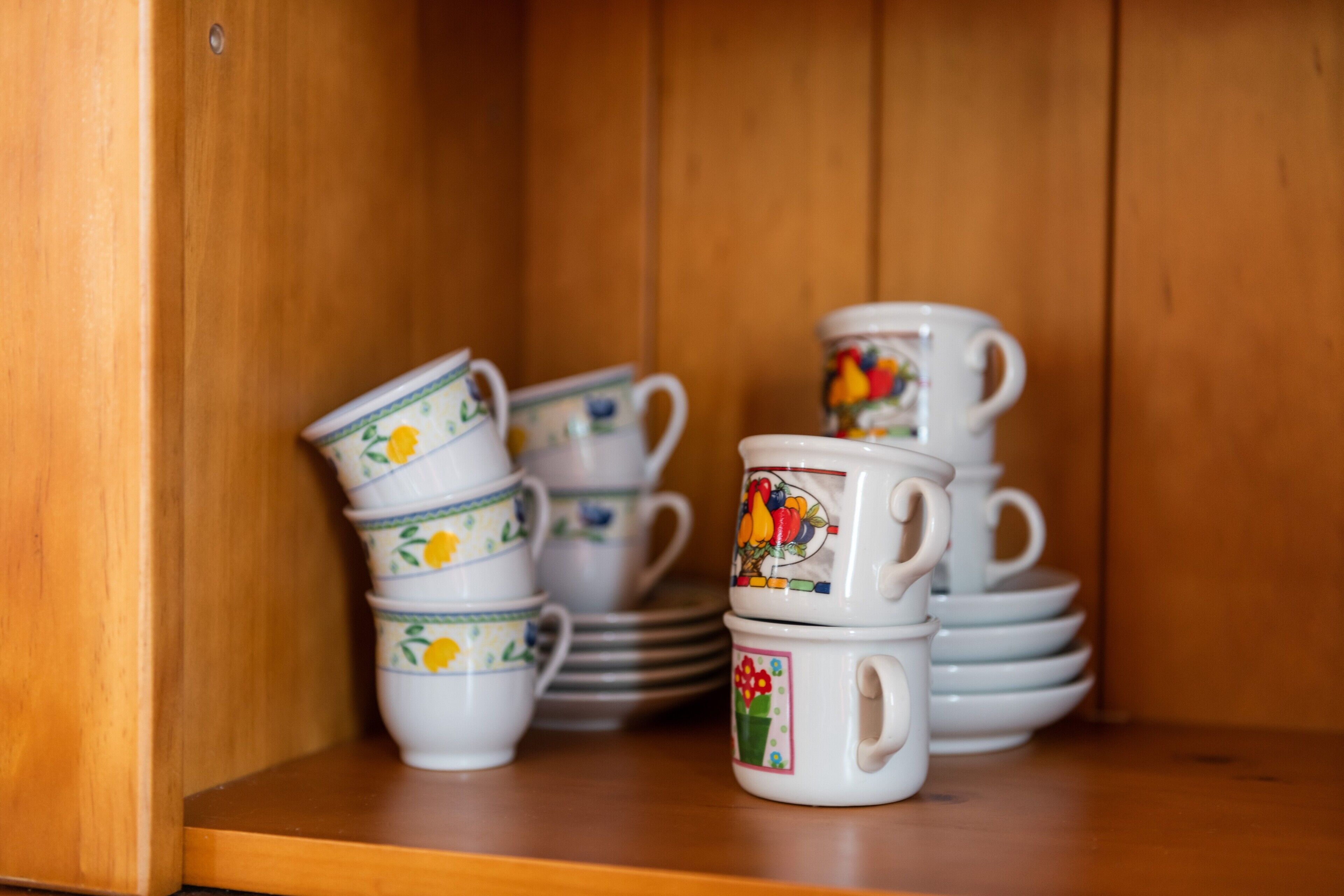 A wooden shelf with stacks of white ceramic cups and saucers.