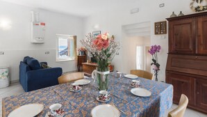 Ein Essbereich mit einem Tisch für vier Personen, einer blauen Tischdecke mit Blumenmuster und einer Blumenvase.
