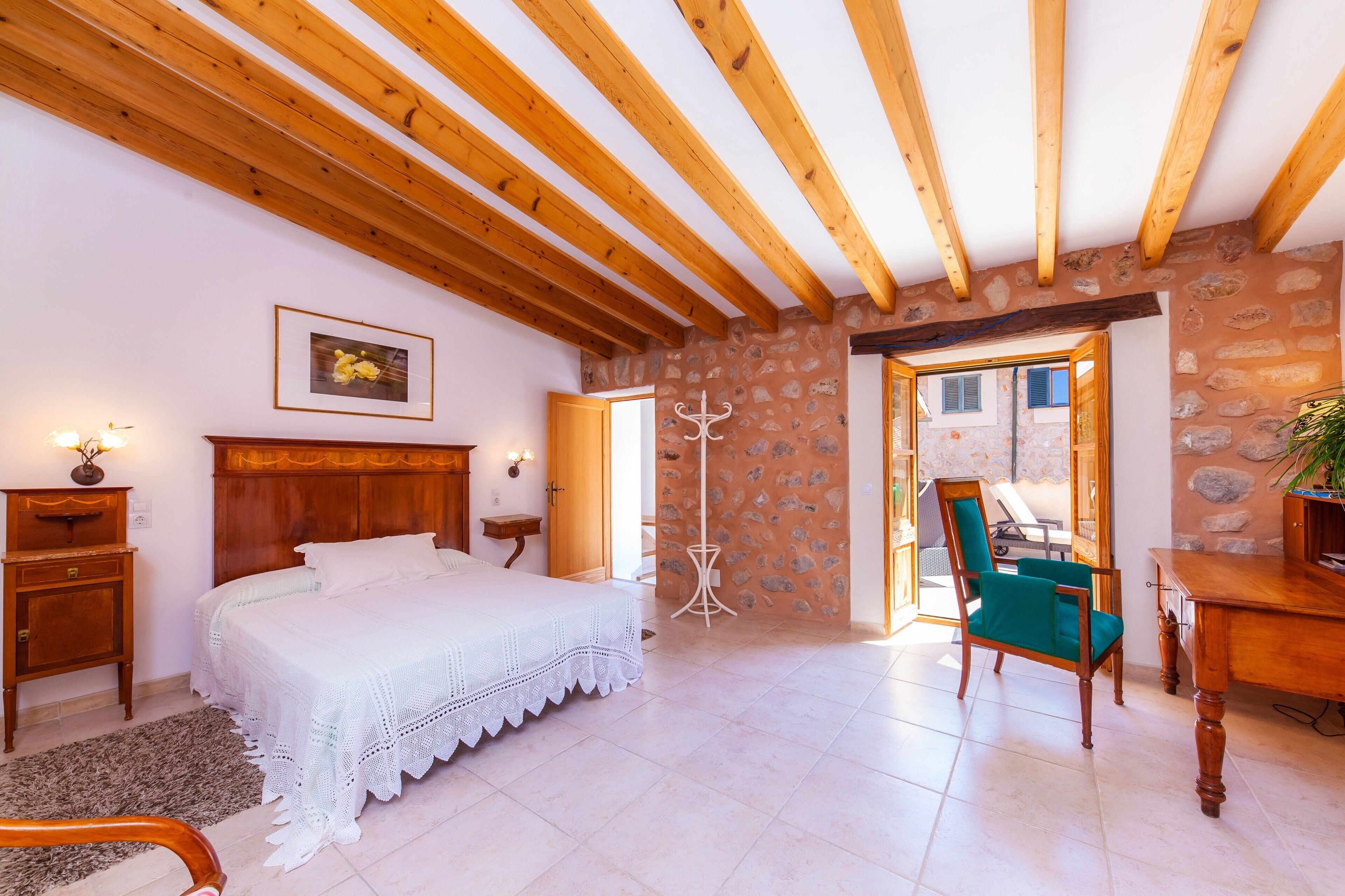 Une chambre avec un plafond en bois, un mur en pierre, un lit, une chaise et une table.