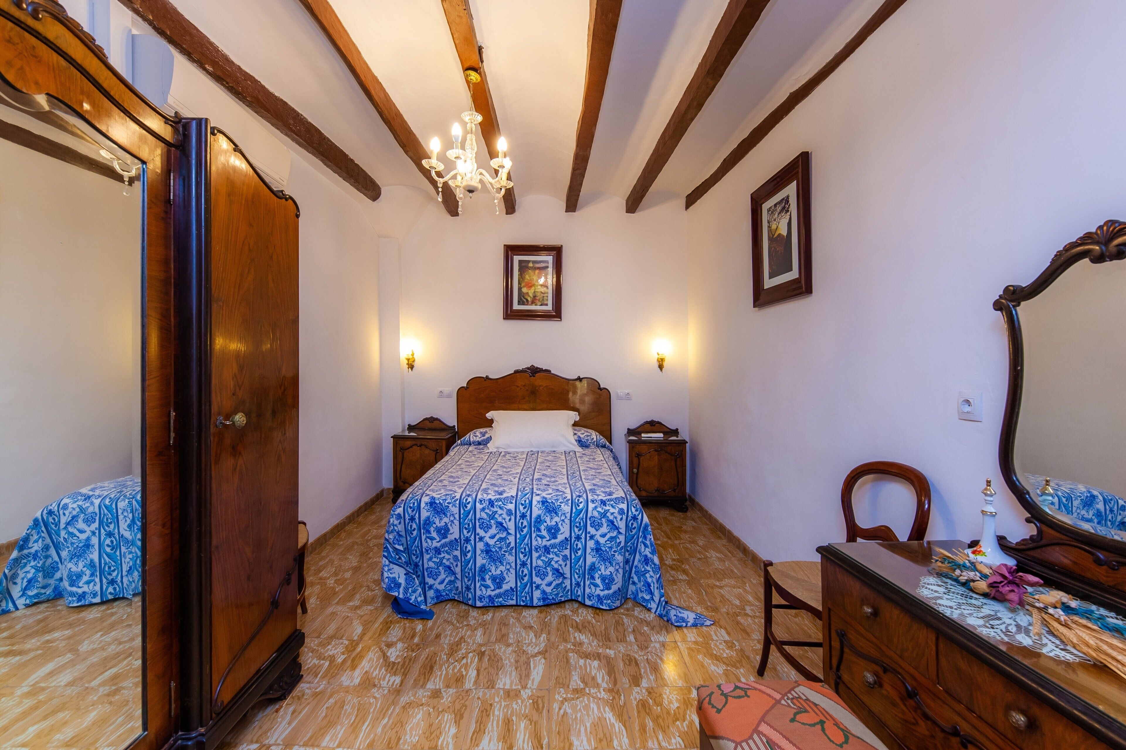 Ein Schlafzimmer mit einem hölzernen Bett, einem Schminktisch, einem Sessel und einem Spiegel.