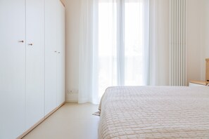 A bedroom with a bed, a wardrobe, and a window with curtains.