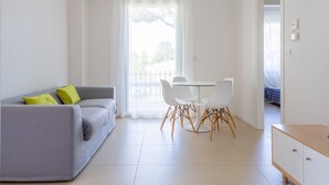 Un salon moderne avec un canapé gris, une table à manger blanche et des chaises.