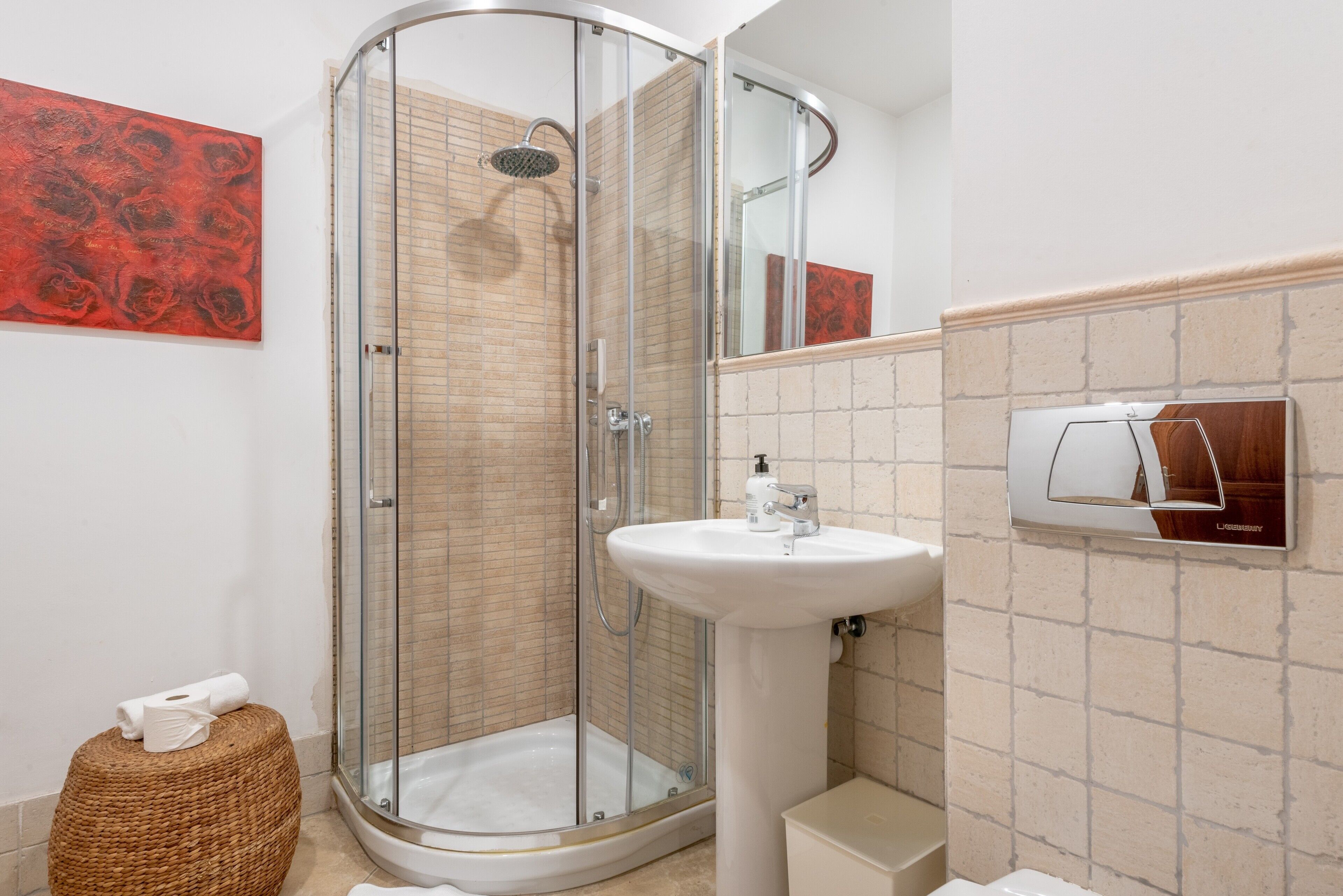 Ein modernes Badezimmer mit Duschkabine aus Glas, einem weißen Waschbecken und einem Spiegel mit Holzrahmen.