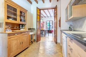 A kitchen with wooden cabinets, a dining area with a table and chairs, and a view through an open door.