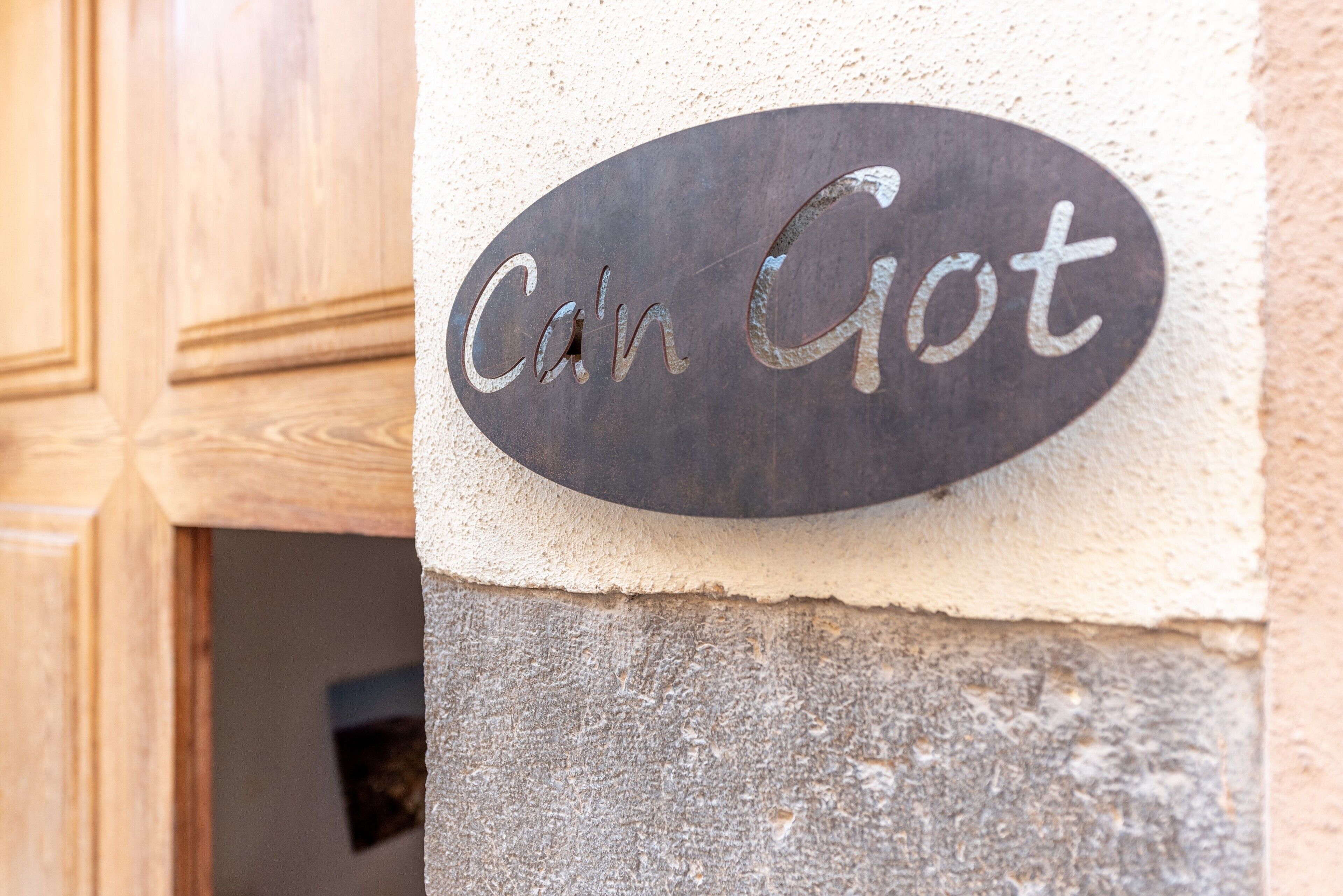 Un cartel de metal con la inscripción 'Can Got' sobre una pared con textura.