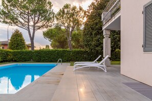 A swimming pool with lounge chairs, a clear sky, and trees. - Modern and with Pool - Apartment Baseventuno 1 (Sirmione)