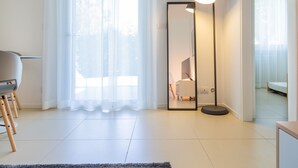 A modern room with a large mirror, a standing floor lamp, and a chair. - Modern and with Pool - Apartment Baseventuno 1 (Sirmione)