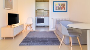 A modern living room with a TV, sofa, and dining table. - Modern and with Pool - Apartment Baseventuno 1 (Sirmione)