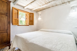 A bedroom with a bed, wooden wardrobe, and a window with open shutters. - Studio 'Casita Estudio El Castaño' with Private Pool, Terrace & Wi-Fi (El Palmar, Vejer de la Frontera)