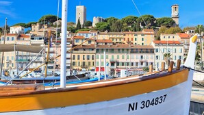 Un barco con el número NI 304837 amarrado en un puerto deportivo con edificios de colores y una torre al fondo.