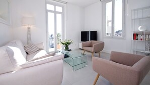 Una sala de estar moderna con una mesa de centro de vidrio, dos sofás, un televisor de pantalla plana y una estantería.