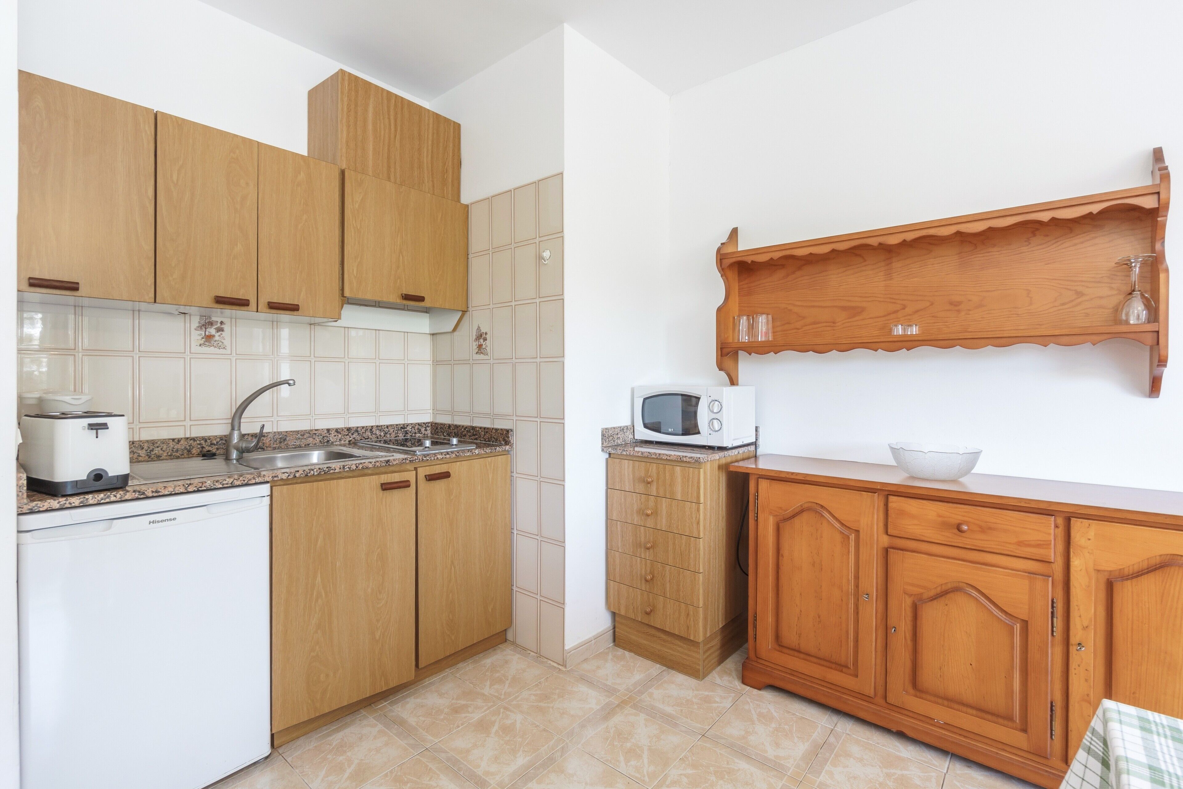 Une cuisine avec des meubles de rangement en bois, un four à micro-ondes, un grille-pain et un évier.