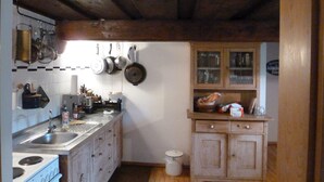 Eine Küche mit Holzausstattung, einem Herd und hängenden Töpfen.