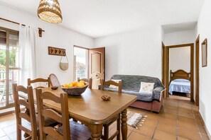 Un comedor con una mesa de madera, sillas, un frutero y una lámpara de mimbre.