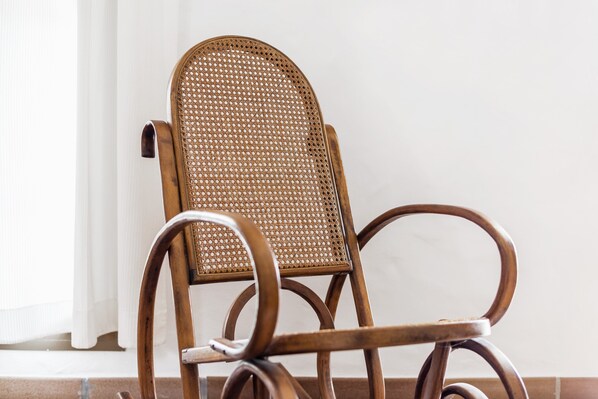 A wooden chair with a woven backrest and armrests.