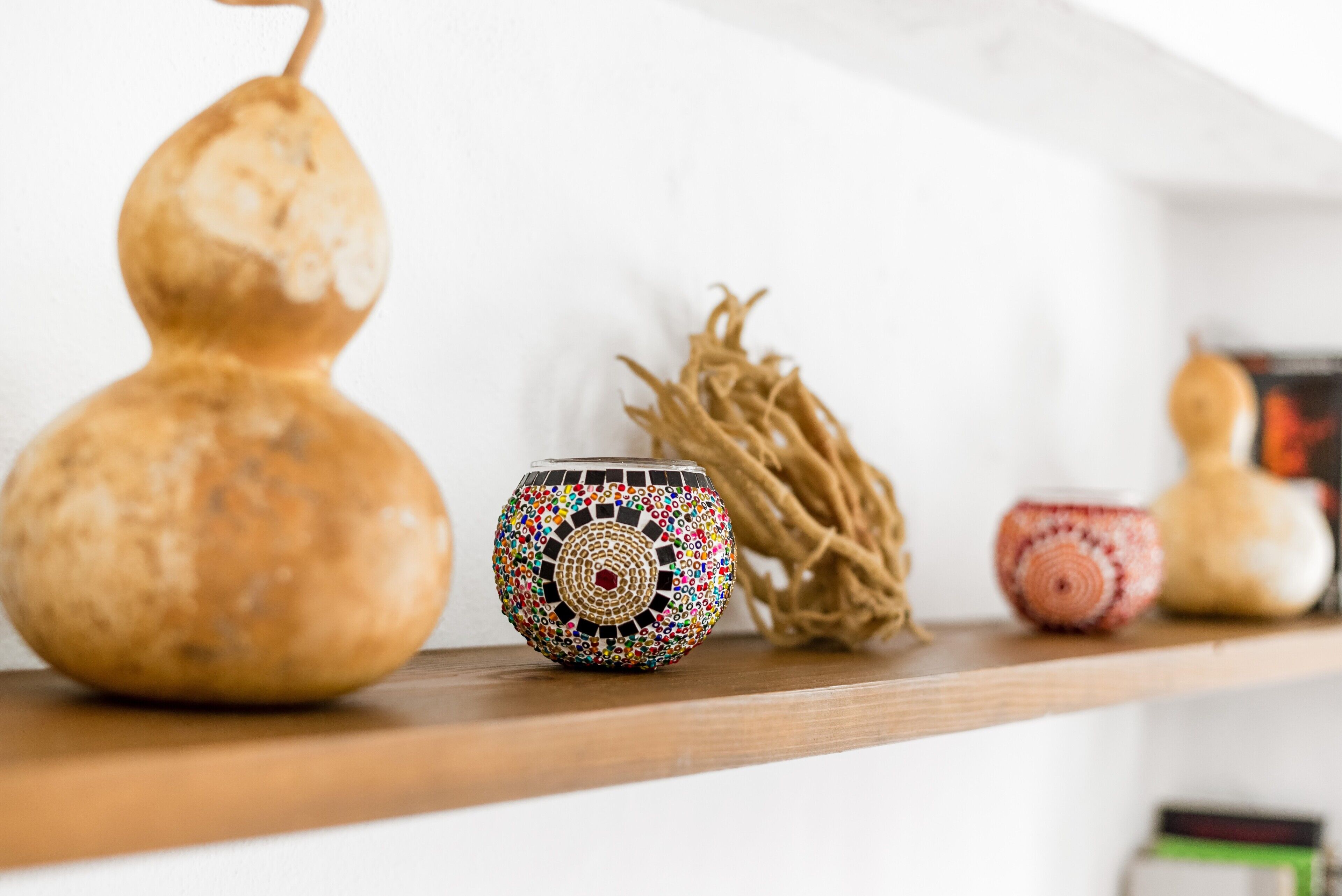 A shelf with decorative items including a gourd, a mosaic bowl, and a small pot.