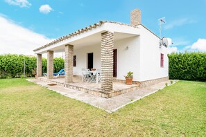 Un edificio blanco con un porche cubierto, columnas y una chimenea.