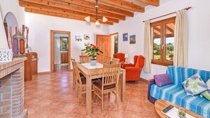 A spacious living area with a wooden dining table, a sofa, and a fireplace.