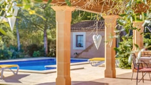 A poolside area with a pergola, a small building with a window, and a heart-shaped decoration.