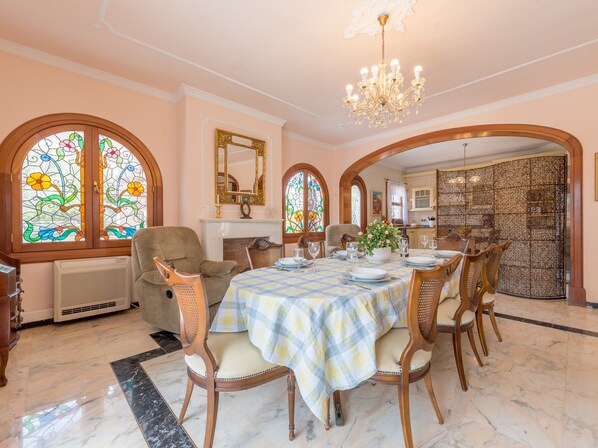 A dining room with a checkered tablecloth, wooden chairs, a chandelier, stained glass windows, and a fireplace. - Luxurious villa with pool - Villa Torre (cala santanyi)