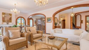 A spacious living room with a glass coffee table, wicker sofas, and a white sofa. - Luxurious villa with pool - Villa Torre (cala santanyi)