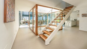 Un interior moderno con una escalera, puertas de cristal, una cocina y un comedor.