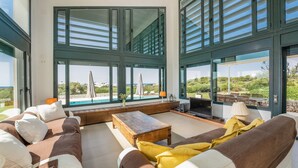 Amplia sala de estar con ventanas grandes, una mesa de centro de madera y un sofá con cojines.