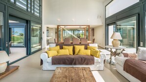 Una sala de estar moderna con un sofá grande, una mesa de centro y un comedor al fondo.