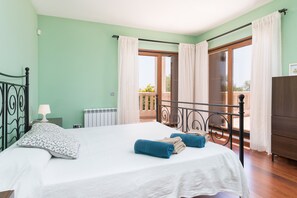 Ein Schlafzimmer mit Bett, Vorhängen, Heizkörper, Fenster und Balkon.