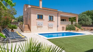 Ein zweistöckiges Haus mit Swimmingpool, einer überdachten Terrasse und einem gepflegten Rasen.