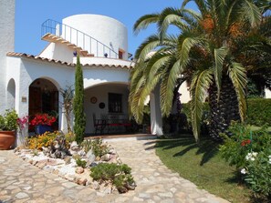 A white building with a curved roof, a stone pathway, and a palm tree. -  Estartit, Typical independent house by the sea, private pool, garden   (Torroella de Montgrí)