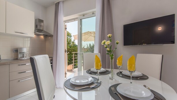 A modern kitchen with a dining area, a flat-screen TV, and a balcony with a view. - Villa Green Palm - Apartment 2 (Vrsar)