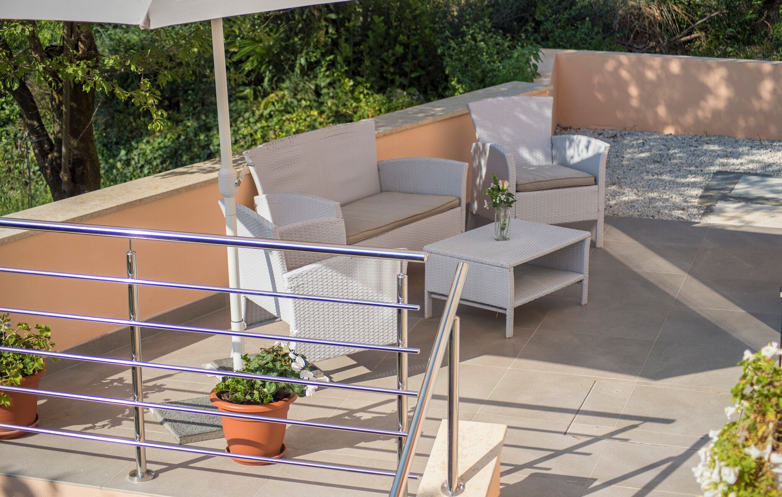 Un patio al aire libre con mobiliario de mimbre, una mesa y plantas en macetas.