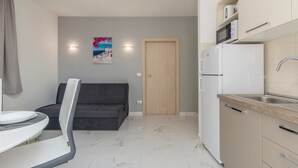 A compact living space with a kitchenette, a sofa, a dining table, and a door leading to another room. - Villa Green Palm - Apartment 2 (Vrsar)