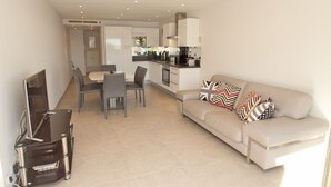 Un salon moderne avec un canapé, un téléviseur et un coin repas.