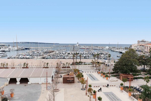 Un port de plaisance où sont amarrés de nombreux bateaux, une zone de stationnement couverte et un bâtiment avec une enseigne.