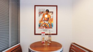 A small round table with a poster, two glasses, and a bottle of wine. - Cruise-1997-We love this studio! (Cannes)