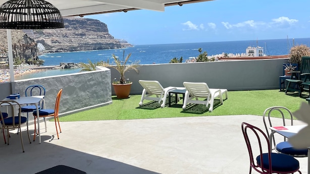 A terrace with a view of the sea, outdoor furniture, and a potted plant. - Pensión Playa Mogán (Mogan)