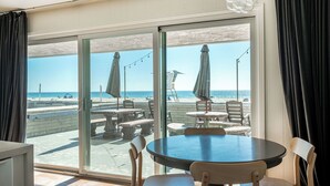 Ein Zimmer mit einer großen Schiebeglastür und Blick auf den Strand, inklusive Sitzgelegenheit und Sonnenschirmen.