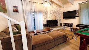 A living room with a sofa, a pool table, a fireplace, and a television. - Tahoe Delight: 5BR, Hot Tub, Sauna, Pool Table & Big Yard ! Close to beach  (South Lake Tahoe)
