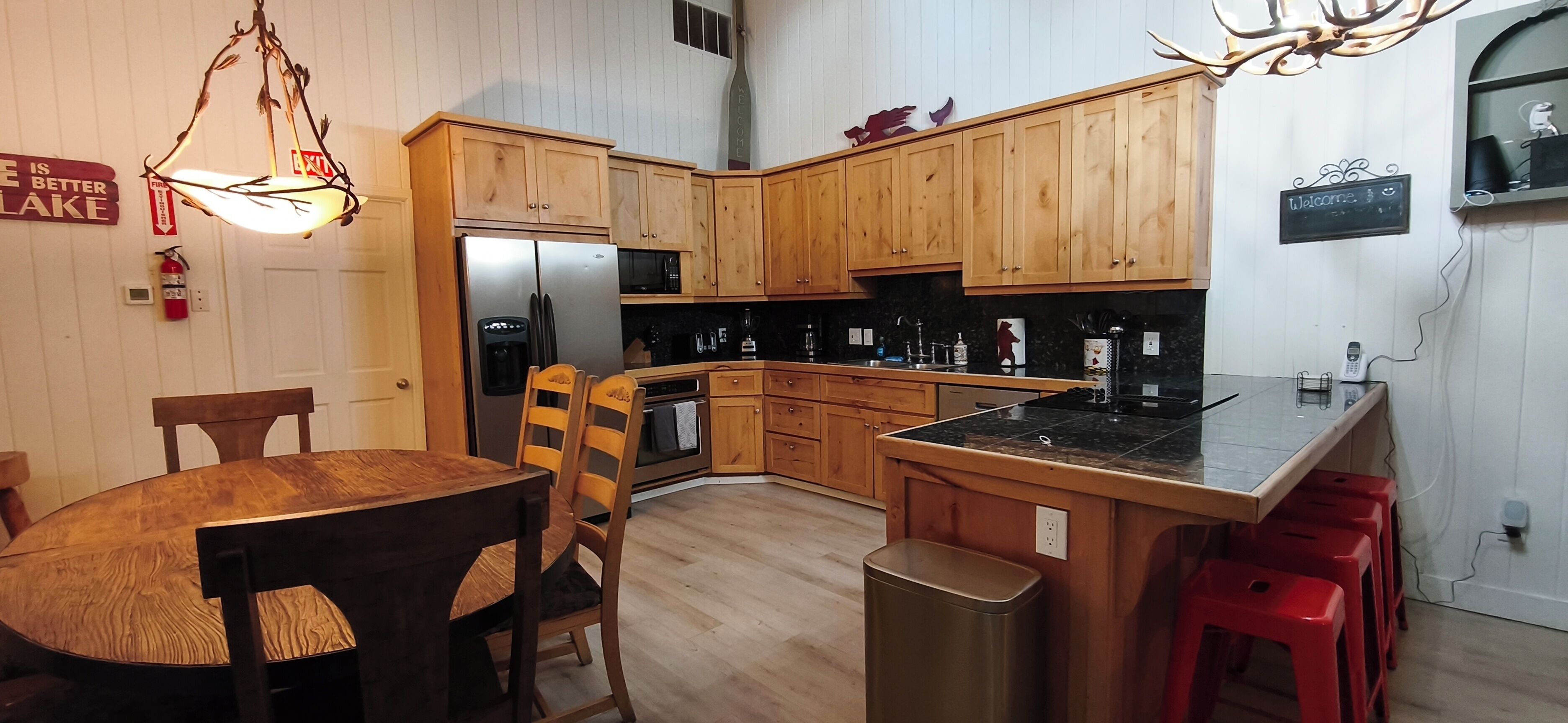 Una cocina con armarios de madera, un refrigerador, un microondas y un lavamanos.