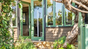 Una casa con un vialetto in pietra che conduce a una porta verde, circondata da vegetazione e un albero.