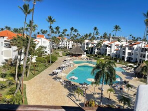 Ein Resort mit zentralem Pool, Palmen und weißen Gebäuden mit roten Dächern.