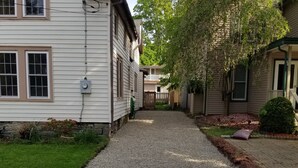 A residential street with houses, a gravel driveway, and a sidewalk. - The Blackberry Inn Guest House (Watkins Glen)